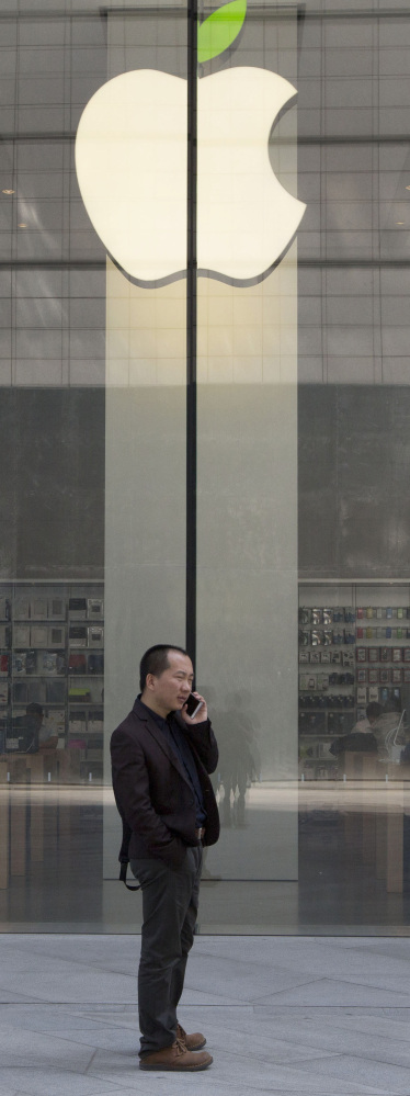 A man uses his phone near an Apple store in Beijing. Since a record close at $133 on Feb. 23, Apple has slumped to $115.40.