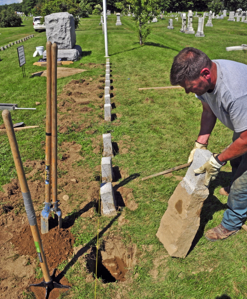 Kevin Miller replaces one of a row of 4-by-4-inch granite markers Wednesday in one of the soldiers’ lots at Mount Pleasant Cemetery in Augusta.