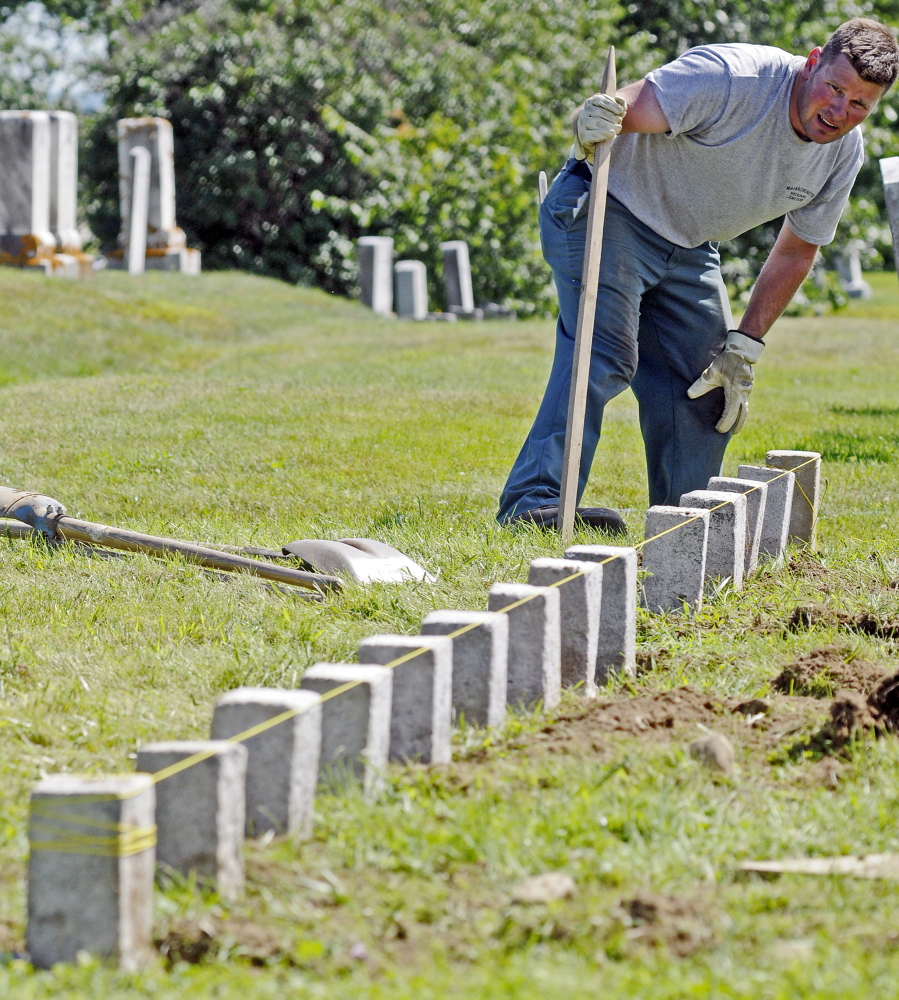 Kevin Miller checks the alignment of a row of granite markers Wednesday in one of the soldiers’ lots at Mount Pleasant Cemetery in Augusta.