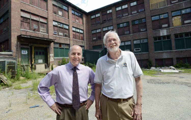 Alan Manoian, left, economic development specialist in Auburn, and Roland Miller, director of planning and development, on Thursday stand in front of the dilapidated shoe factory on Minot Avenue in Auburn that Chinese investors announced they plan to convert into a health and wellness hotel aligned with Central Maine Medical Center in Lewiston.