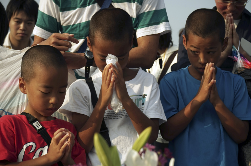 Children pray for the atomic bomb victims in front of the cenotaph at the Hiroshima Peace Memorial Park in Hiroshima, Japan, early Thursday as Japan marked the 70th anniversary of the atomic bombing of Hiroshima.