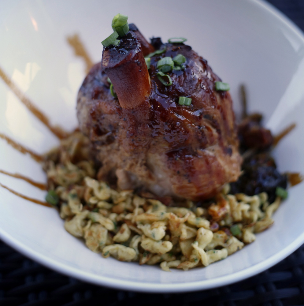 The pork shank is served with herbed spaetzle and braised bitter greens.