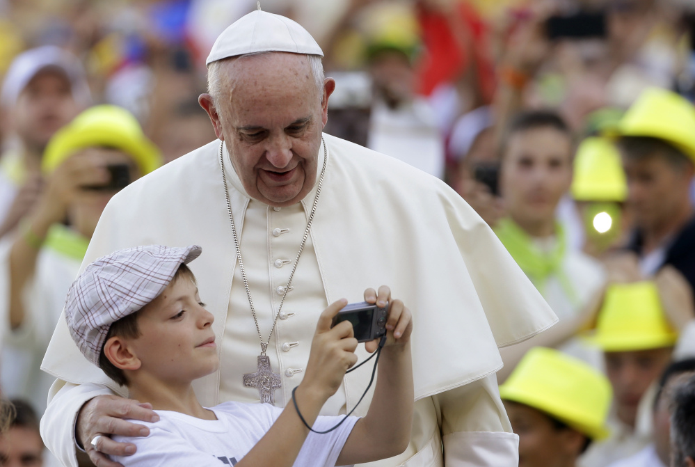 Pope Francis is shown his portrait taken by a boy as he arrives in St. Peter’s Square at the Vatican for an audience with altar boys and girls Tuesday. The pontiff says children are damaged when their parents feel shunned by the church.