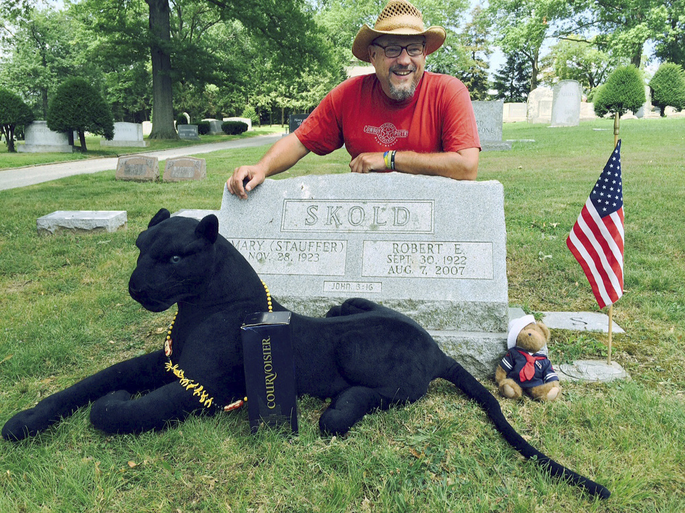 Walter Skold of Freeport poses Friday at the grave of his father in York, Pa. The Dead Poets Society of America founder visited his father’s grave after completing his summer tour of 97 poets’ graves in 70 days. With Skold is his mascot Raven, a stuffed black panther that was given to him.