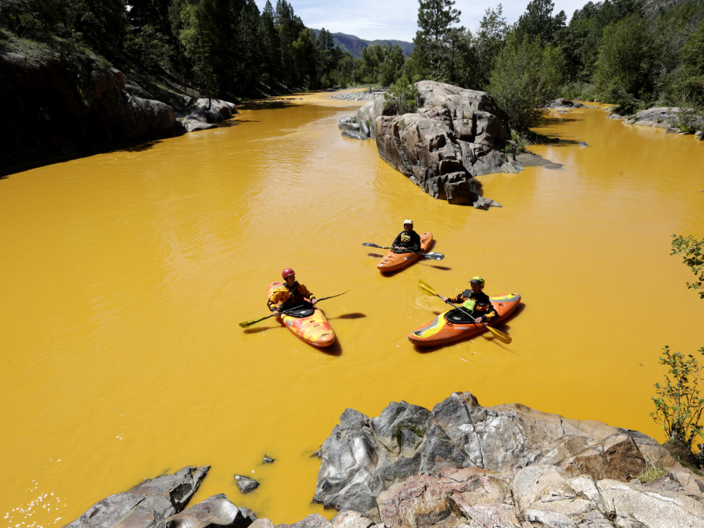 People kayak in the Animas River near Durango, Colo., in water colored from a mine waste spill.
