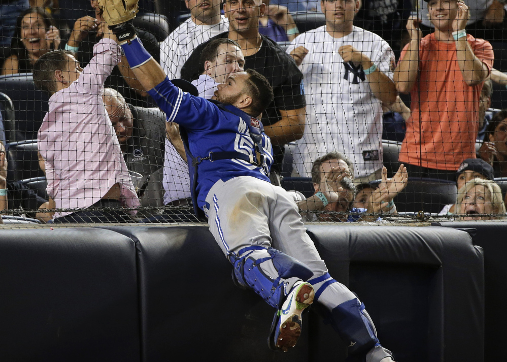Blue Jays catcher Russell Martin catches a foul pop as he leaps against the backstop netting during the seventh inning of Toronto’s 2-1, 10-inning victory over the Yankees at New York.