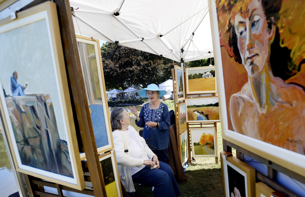 Ginny Nickerson, back right, and Margette Leanna talk in Leanna’s tent during Art in the Park at Mill Creek Park in South Portland on Saturday.