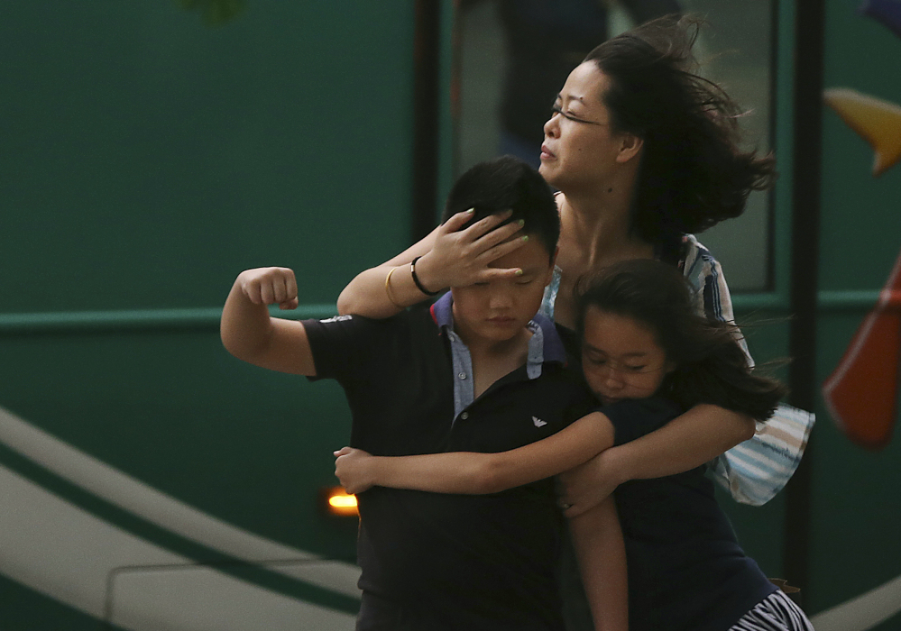 A mother holds her children as Typhoon Soudelor strikes Friday in Taipei, Taiwan. The storm left six dead there and was battering southeast China by late Saturday.