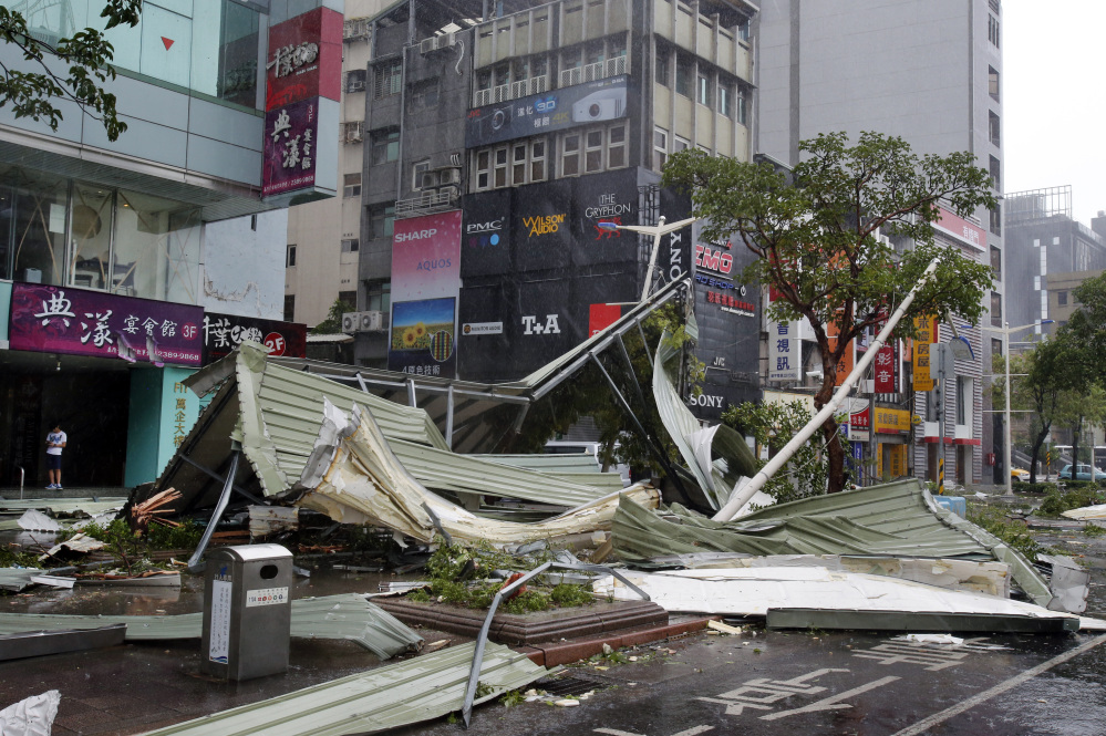 A street corner is filled with a mangled rooftop brought down by strong winds from Typhoon Soudelor in Taipei, Taiwan, Saturday. Soudelor’s wind speeds topped 100 mph, with gusts over 120 mph, according to Taiwan’s Central Weather Bureau. 