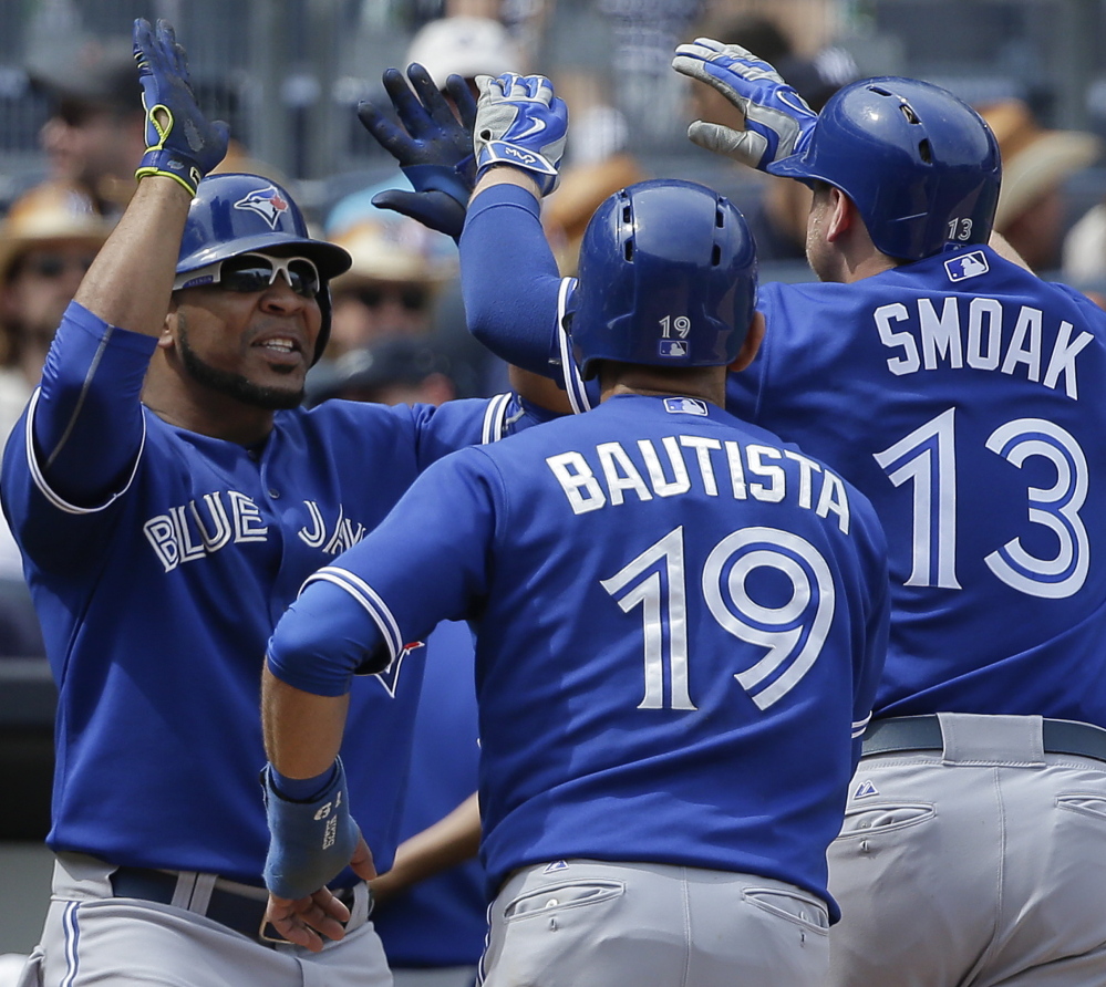 Toronto’s Edwin Encarnacion, left, greets Jose Bautista and Justin Smoak after Smoak hit a grand slam during a 6-0 win over the Yankees in New York.