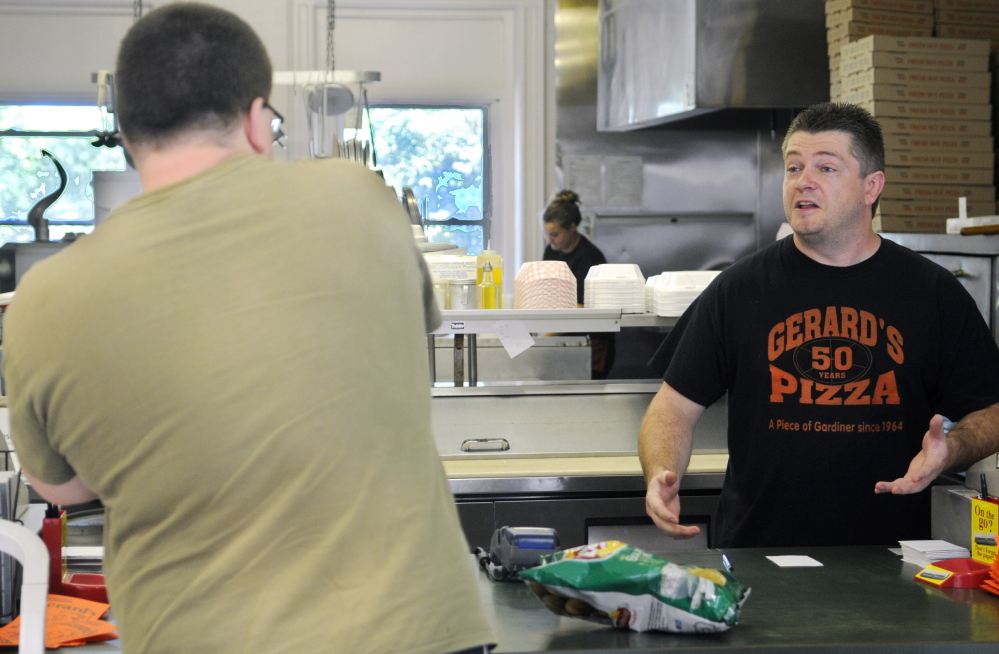 Gerard’s Pizza proprietor Jeff McCormick speaks with customer Ben Tracy on Monday at the counter of the Gardiner pizza parlor that had closed after the July 16 fire.