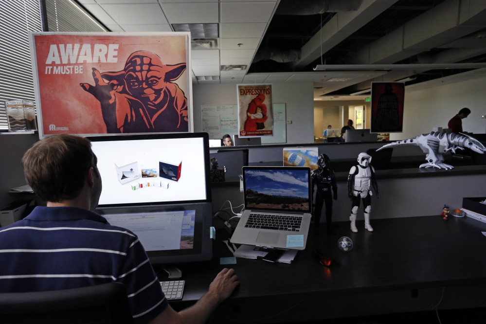 In this July 24, 2015 photo, an employee at Sphero, a fast-growing toy robotics company, works surrounded by Star Wars toys and posters, at the company headquarters in Boulder, Colo.