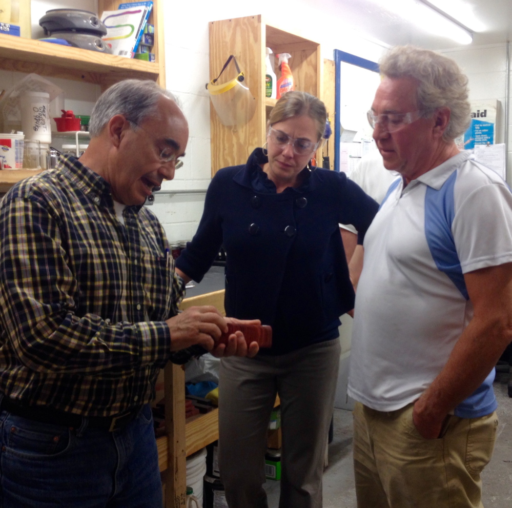 Rep. Bruce Poliquin looks at a product made by Cousineau Wood Products in North Anson with Samantha Warren, his district director. At right is Randy Cousineau, the company’s CEO.