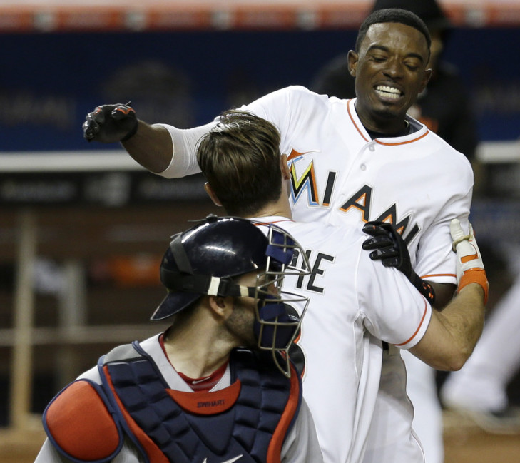 The Marlins’ Dee Gordon is lifted by teammate Cole Gillespie after scoring the game-winning run on a base hit by Justin Bour in the 10th inning Tuesday night in Miami. The Marlins won 5-4.