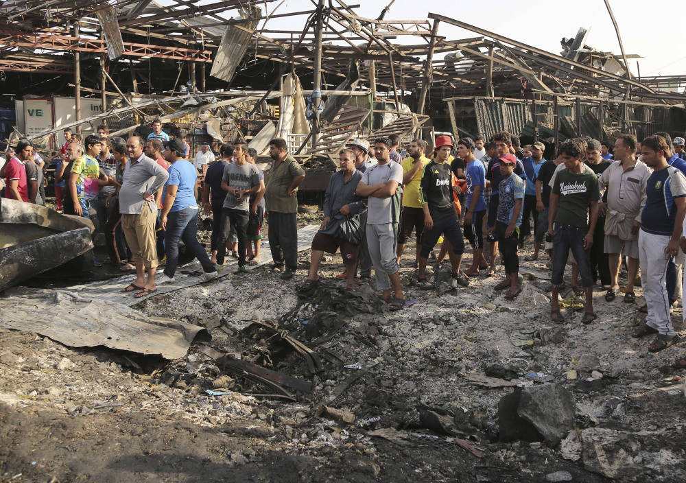 Civilians gather Thursday at the scene of a truck bombing in Baghdad’s Jameela market. The truck bomb ripped through the popular food market in the early-morning hours Thursday, killing 67 people.