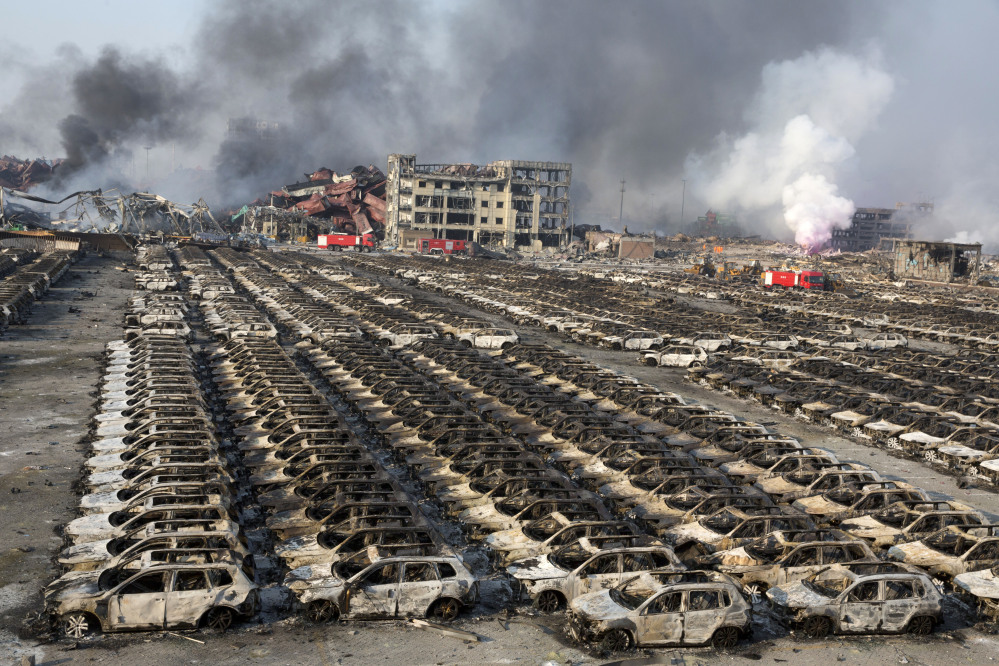 Smoke billows Thursday from the site of an explosion that reduced a parking lot filled with new cars to charred remains in northeastern China’s Tianjin municipality. Huge explosions in the warehouse district sent up massive fireballs that turned the night sky into day, officials and witnesses said Thursday.
