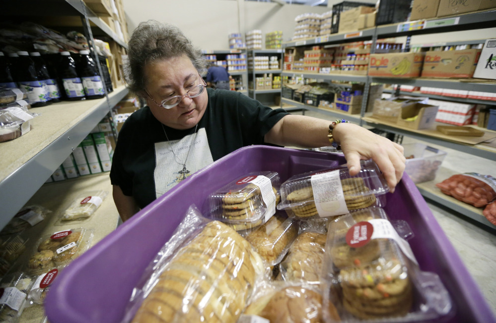 Volunteer Peggy Bragg of Des Moines, Iowa, unloads donated baked goods at the Des Moines Area Religious Council food pantry in Des Moines, Iowa. Because of rising demand, some charities are reducing the amount of food they offer each family.