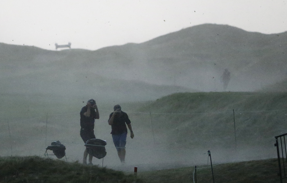 Fans scramble for cover from a storm that caused play to be suspended Friday before the second round had been completed. Play will resume at 7 a.m. Saturday.