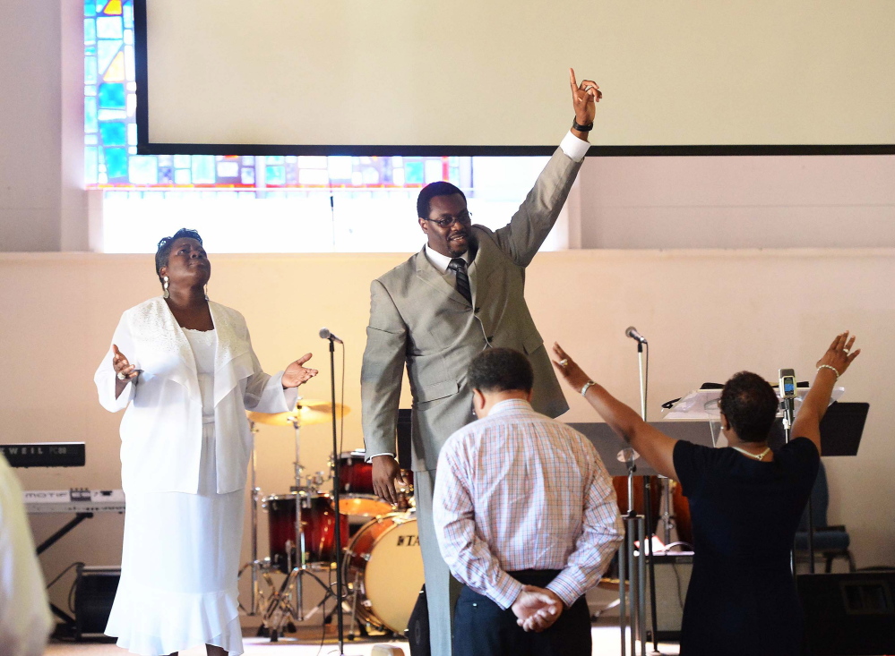 Co-pastor Rhonda Kinsey, left, and senior pastor Mannix Kinsey lead the congregation during a Sunday service at Briar Creek Road Baptist Church in June in Charlotte, N.C. An entire wing of the church was destroyed by an intentionally set fire.