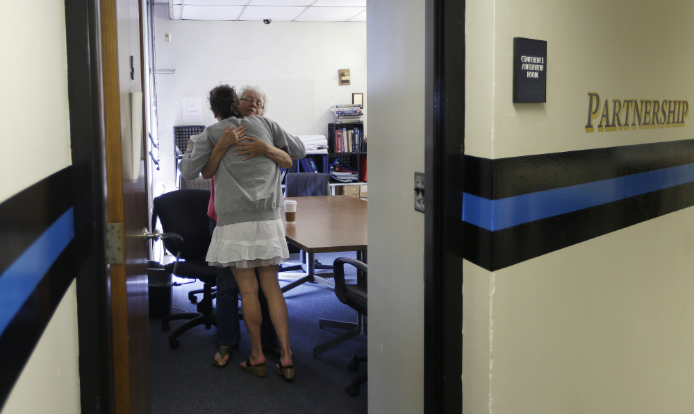 Inside the police station in Gloucester, Mass., volunteer Ruth Cote, facing, hugs a woman who has voluntarily come to the police for help kicking her heroin addiction. Gloucester is taking a novel approach to the war on drugs.