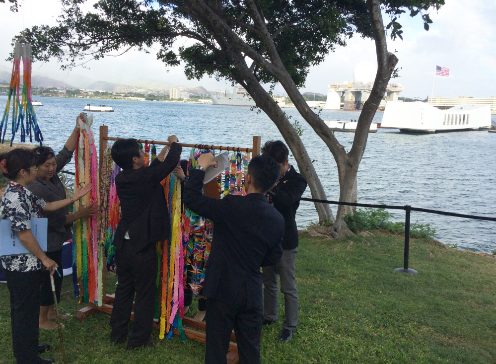 People hang paper cranes folded for peace near a memorial to the sunken battleship USS Arizona before a ceremony marking the 70th anniversary of the end of World War II, on Friday