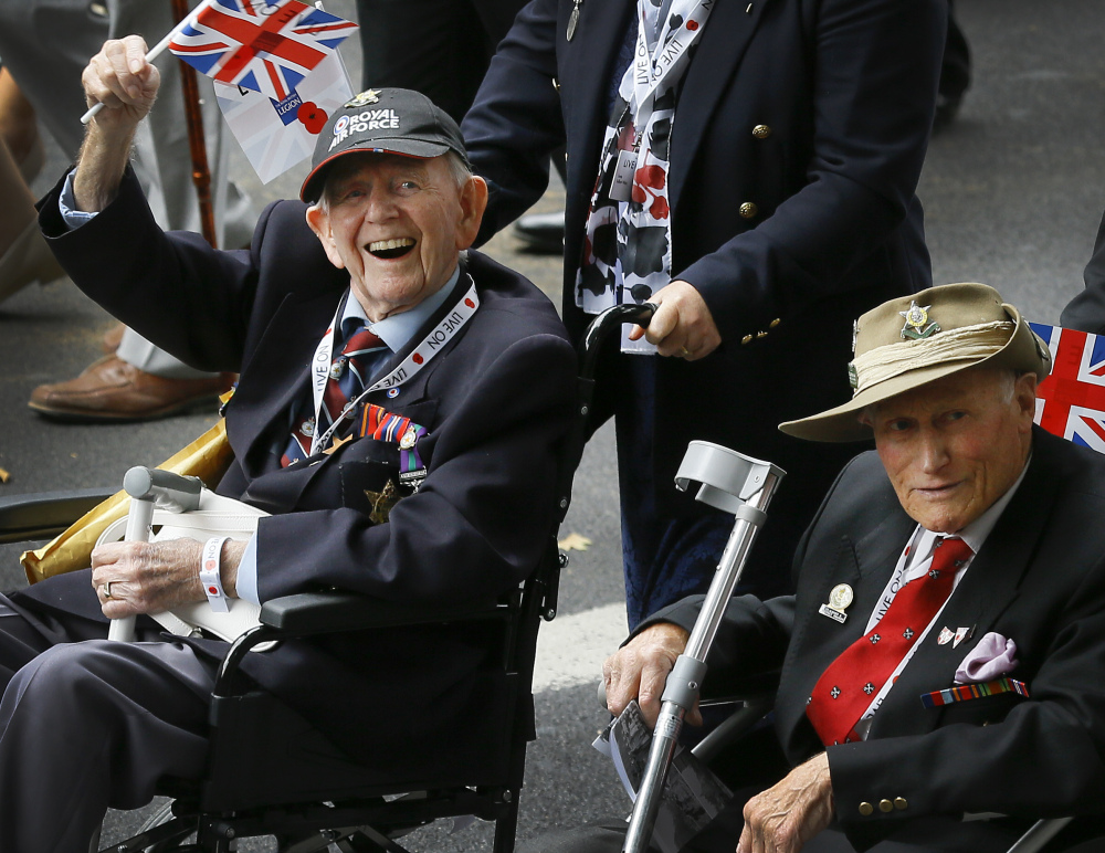 A veteran waves a flag during the parade to commemorate VJ day, as the parade passes along Whitehall in London on Saturday. Thousands cheered on the veterans of Britain’s 4  -year campaign in Asia.