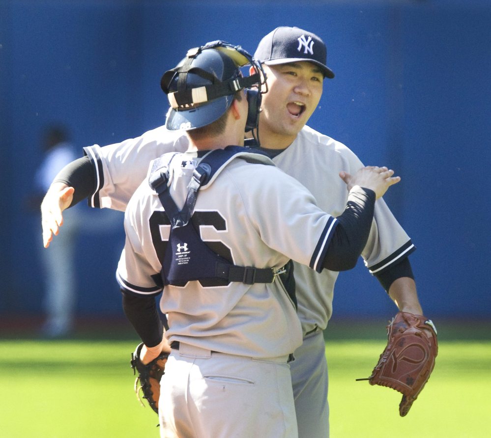 Yankees’ starting pitcher Masahiro Tanaka embraces catcher John Ryan Murphy after finishing a five-hitter for a 4-1 victory at Toronto.