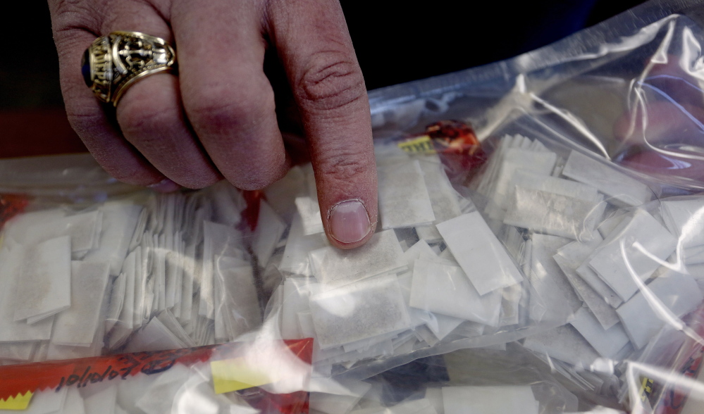 Scott Pelletier of the Maine Drug Enforcement Agency shows heroin packets the agency seized Feb. 11, 2014. Gov. Paul LePage takes an enforcement-centric view of the state’s growing heroin problem.