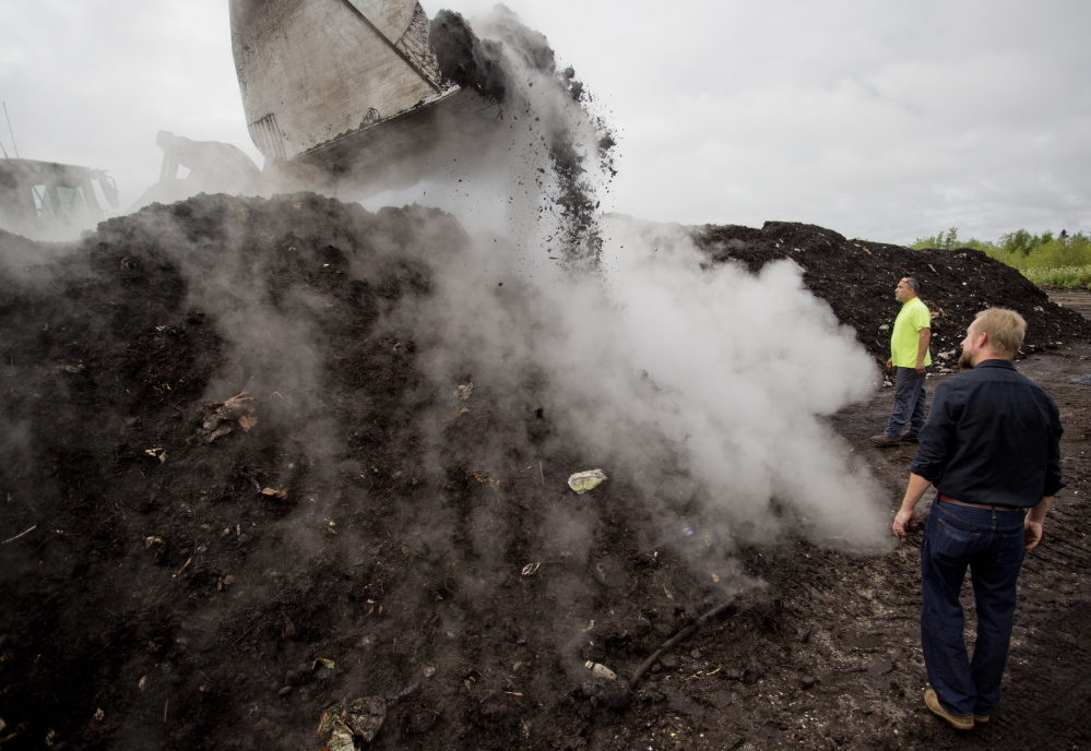 Leo Amara, of debris recycler CPRC Group, and Brett Richardson of We Compost It! watch as an excavator turns compost at a facility in Auburn. The compost cooks at about 160 degrees, causing steam to release when it is turned.