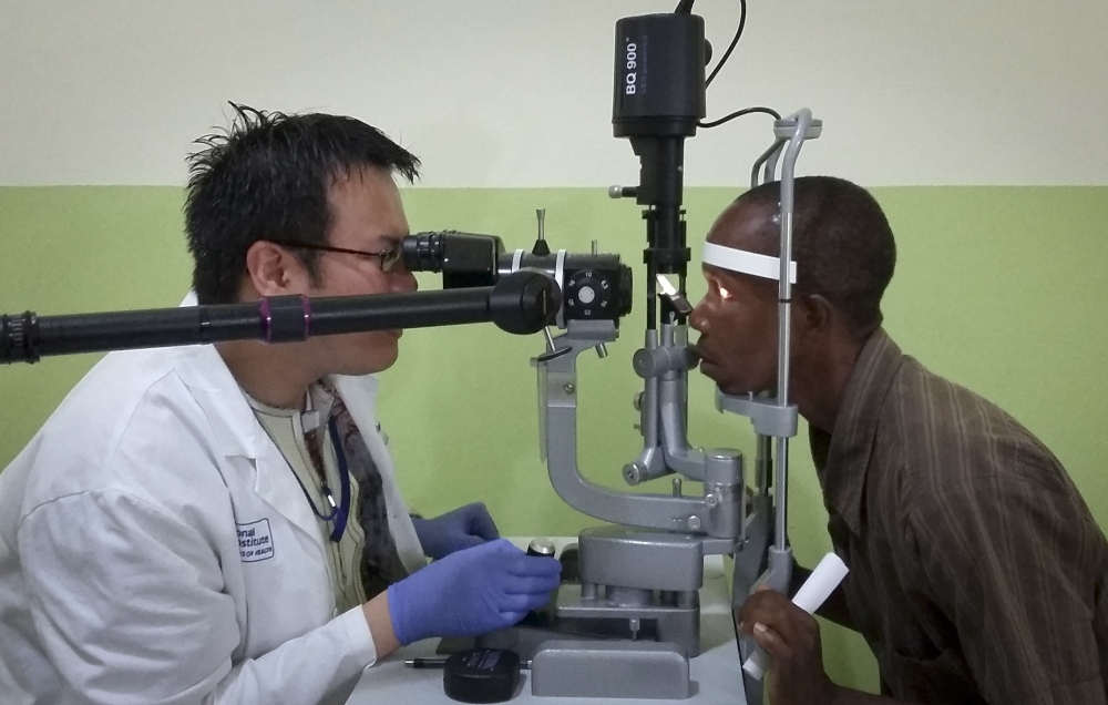 Dr. Ian Yeung, left, an eye specialist for a joint Liberian-American Ebola project, examines the eyes of Ebola survivor Abraham Moses, who has problems with his vision, in Monrovia.