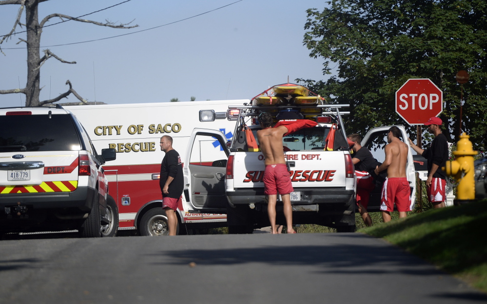 Lifeguards and rescue personnel gather at the end of Dune Avenue in Saco while responding to reports of people caught in rip currents Monday.