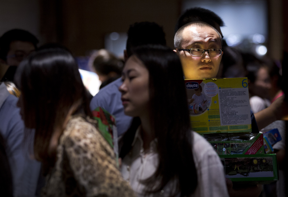 A man waits in line near a cashier counter at a shopping mall in Beijing. China is trying to engineer an economic transition from rapid growth fueled by exports and often-wasteful investment to slower growth built on consumer spending.