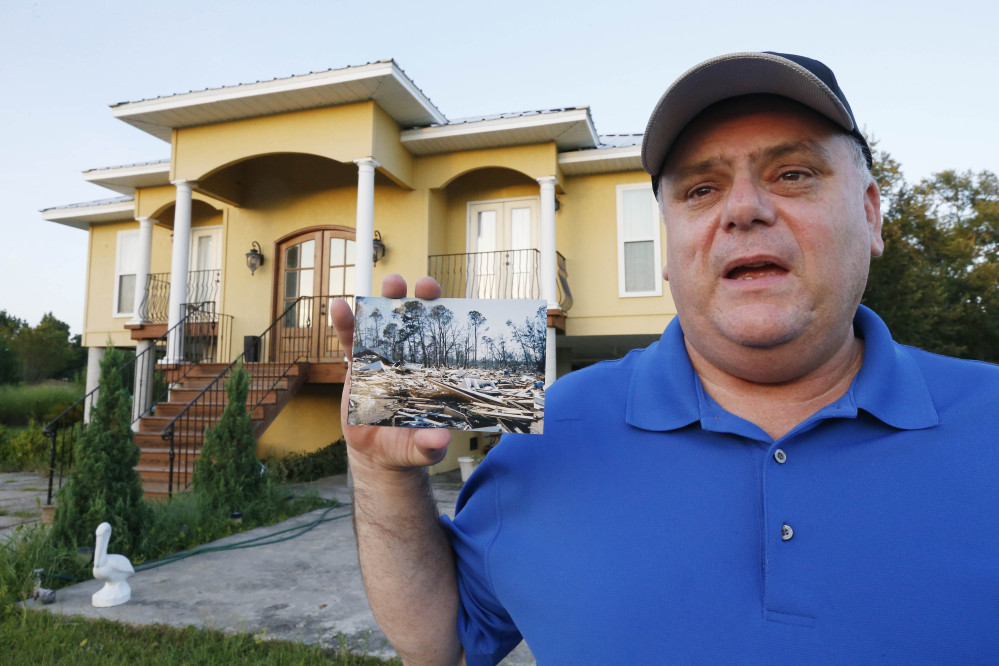 Efrem Garza stands before his new home built on the lot of his previous house that was destroyed by Hurricane Katrina. He holds a photograph taken by a friend showing the remains of his previous house on South Seashore Avenue in Long Beach, Miss. Before the storm Garza was surrounded by houses and trees, now 10 years later, there are only two houses on that land, as few of the residents returned and rebuilt.
