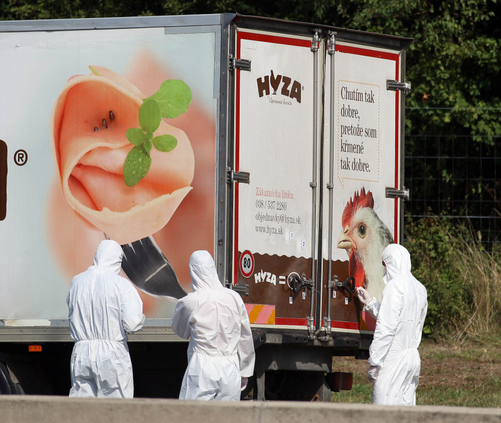 Investigators stand near a truck on the shoulder of a highway near Parndorf south of Vienna, Austria, Thursday. At least 20 migrants were found dead in the truck.