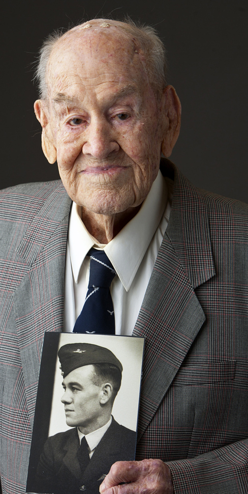 “Great Escape” survivor Paul Royle poses holding a photo of himself in uniform during World War II.