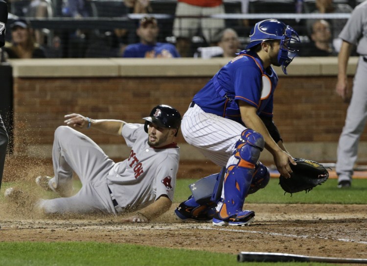 Blake Swihart slides past New York Mets catcher Travis d’Arnaud to score on an inside-the-park home run in the 10th inning Friday night in New York.