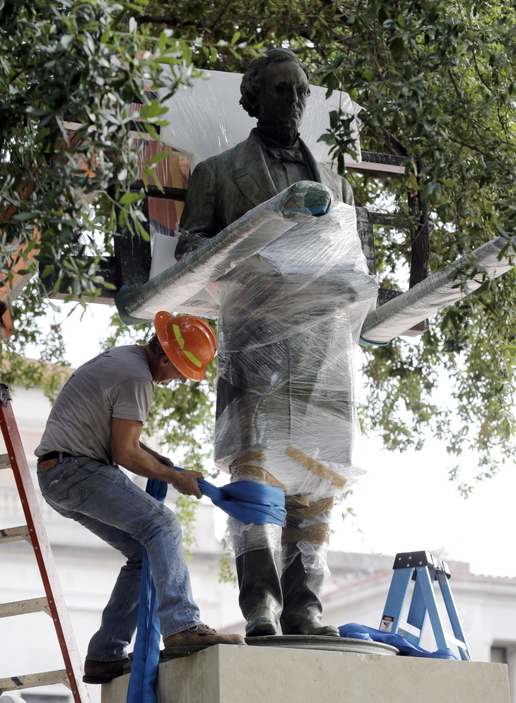 Workers wrap protective materials around a statue of Confederate President Jefferson Davis as they prepare to move the sculpture on the University of Texas campus Sunday. The Davis statue, which has been targeted by vandals and had come under increasing criticism, will be placed in the school’s Dolph Briscoe Center for American History as part of an educational display. 