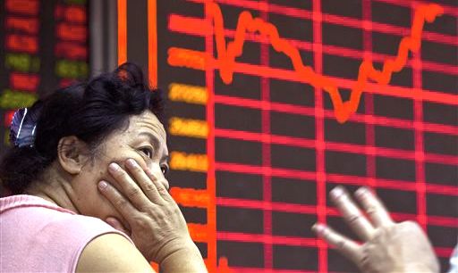A Chinese investor monitors stock prices at a brokerage in Beijing on Wednesday. Asian stocks were mixed Wednesday and Shanghai's index fell despite Beijing's decision to cut a key interest rate to help stabilize gyrating financial markets and counter short liquidity. The Associated Press