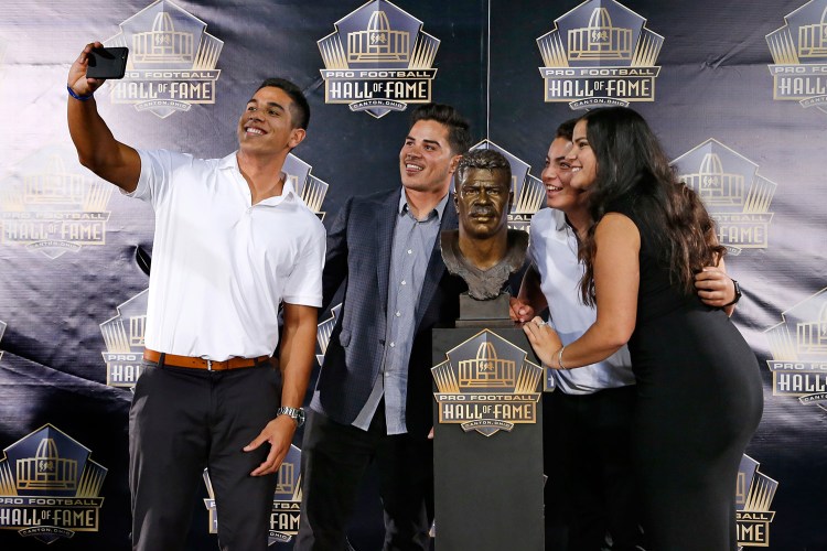 Children of former NFL player Junior Seau, from left, Jake, Tyler, Hunter and Sydney pose for a selfie with the bust of their late father, during inductions at the Pro Football Hall of Fame on Aug. 8 in Canton, Ohio.  The Associated Press