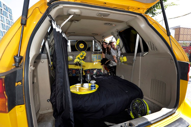 Airbnb renters Michael and Tabitha Akins, and their dog Bagheera, check their accommodations in a decommissioned 2002 Honda Odyssey yellow taxi, in New York City.