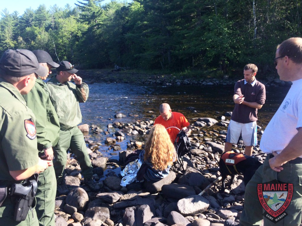 Tending to Erica LaChance, who is sitting, are Maine game wardens, from left, William Shuman, Tom McKenney and Jared Herrick, and Walter Glynn of the West Forks Fire Department, along with an unidentified acquaintance and Sgt. Chris Simmons, on Monday.