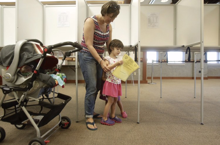 Isabel Alves, 4, looks at the ballot for the Scarborough school budget vote while her mother, Laurie Alves, votes at the Scarborough Municipal Complex on Tuesday. It was the third time Alves has voted for the school budget, which she says she would like to see approved so no school programs get cut. 