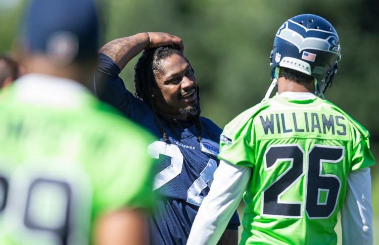 Seattle Seahawks running back Marshawn Lynch, center, talks to defensive back Cary Williams during an NFL football training camp on July 31 in Renton, Wash. The Associated Press