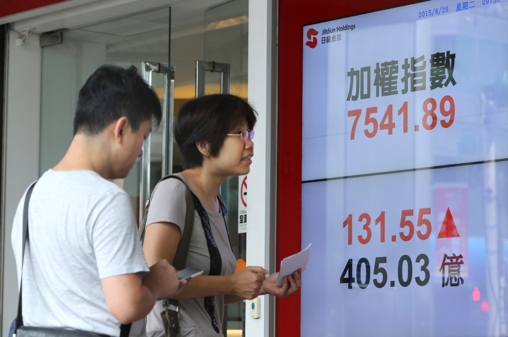 Pedestrians watch monitors displaying the benchmark of the Taiwan Stock Exchange in Taipei on Tuesday. Chinese stocks plunged again Tuesday morning, a day after the country's main benchmark suffered its biggest tumble in eight years.
The Associated Press