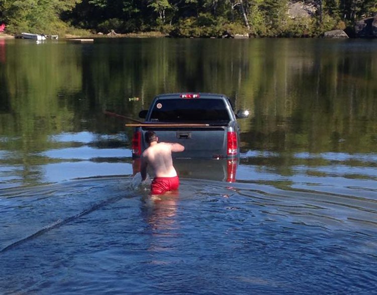 A man wades out to his truck after it rolls into Branch Lake near Ellsworth with his dog inside the cab. Photo courtesy of Ellsworth Police Department