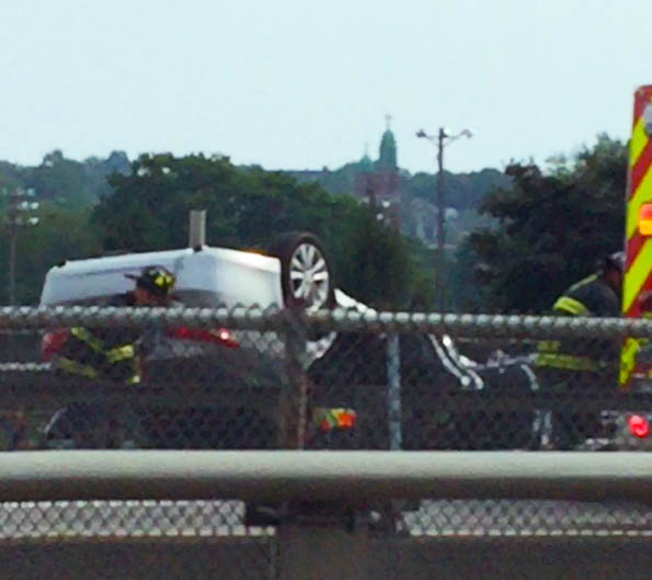 A rescue crew works on Interstate 295 in Portland after a car flipped onto its roof Thursday afternoon.