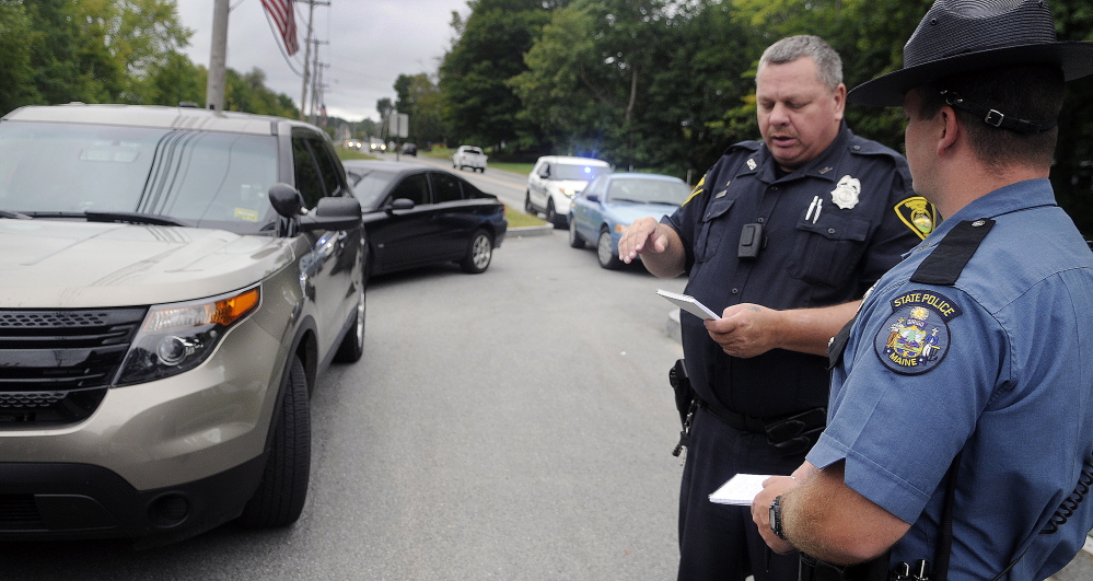 Gardiner Police Officer Eric Testerman, left, shares information with State Trooper Randy Hall Sunday on the Kennebec River Rail Trail in Farmingdale about a suspect involved in an assault on the trail. A man was transported to the hospital by ambulance following the assault that occurred before 10 a.m. across from Sheldon Street, police said.