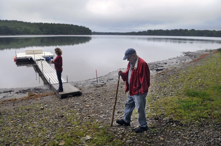 Stan Whittier walks on the shore of Clary Lake in Jefferson while his daughter, Jane Roy, stands on the family’s dock. It’s been nearly three years since property owners around Clary Lake in Jefferson and Whitefield appealed to the state to intervene over a low water level, and residents say the situation still hasn’t improved.