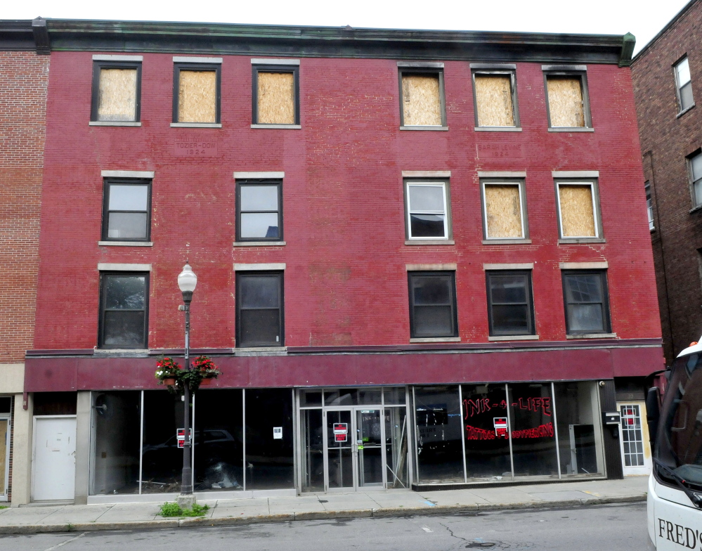 An apartment building and former pawn shop remain boarded up and vacant since fire heavily damaged the building on Main Street in Waterville.