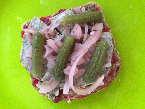 Lingonberry-rosemary sauce peeks out from the bottom of an open-faced sandwich with pork pâté, pickled red onions and cornichons.